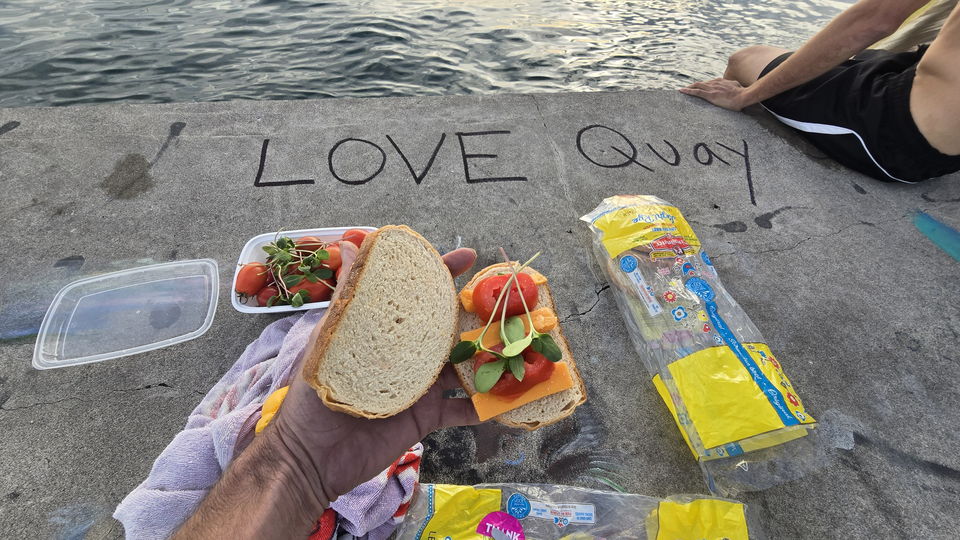 The words LOVE Quay written in chalk on the concrete deck beside a picnic laid out on the pier