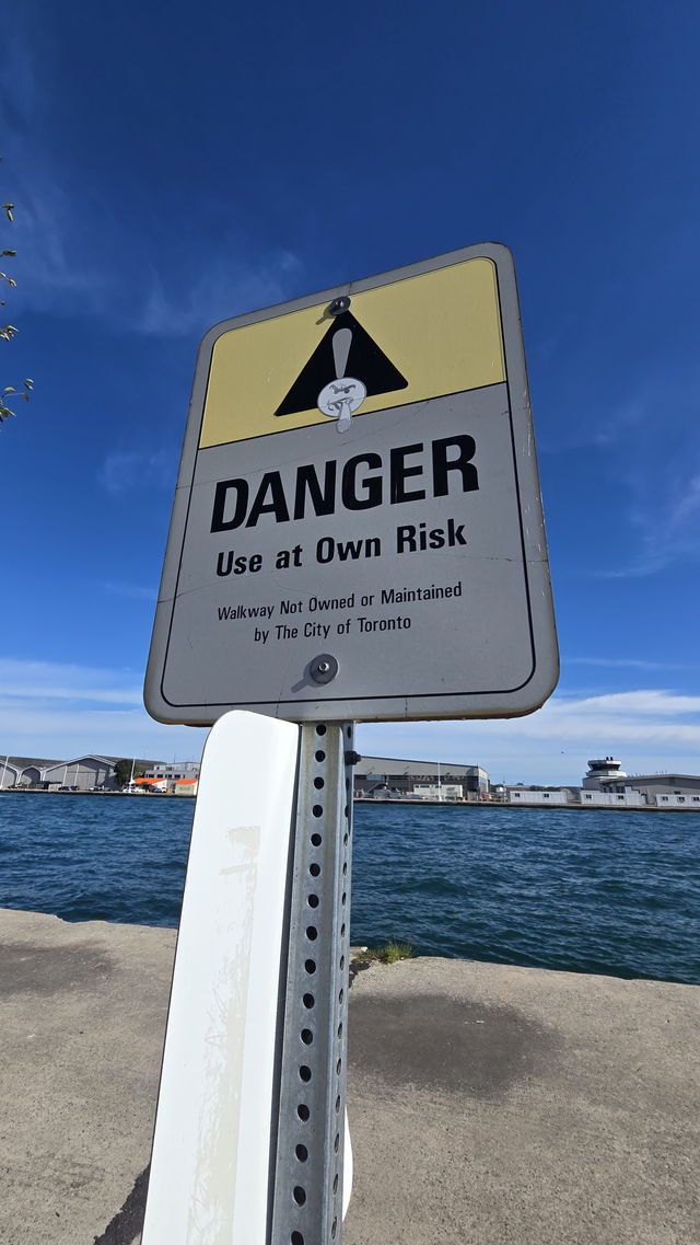 A Danger, Use at Own Risk sign on a post at the very edge of the pier, open water behind it
