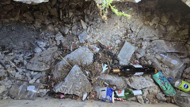 Broken concrete and washed-up litter along the rubble edge of the quay