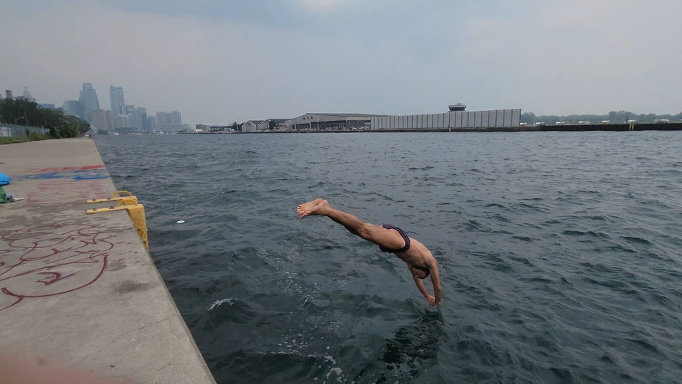 A swimmer mid-dive off the westernmost end of LoveQuay into Lake Ontario