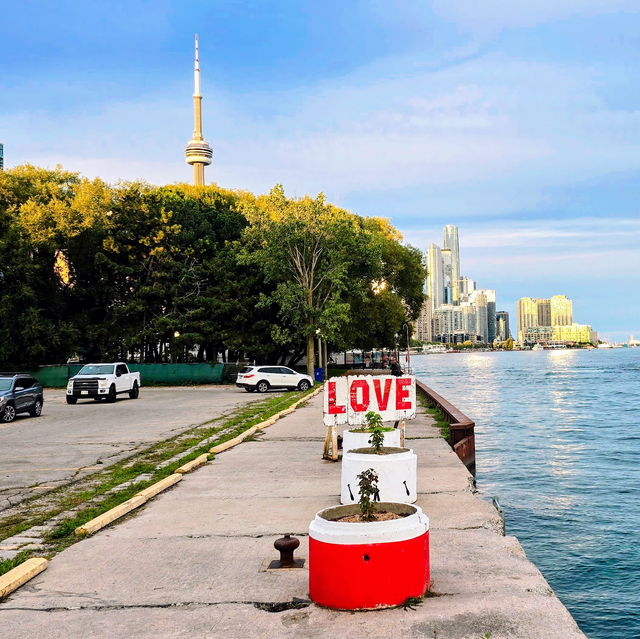 A red and white bollard painted with the word LOVE on the pier, CN Tower in the distance