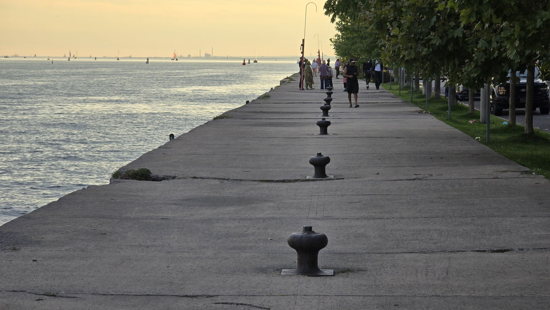 The LoveQuay pier stretching west into Lake Ontario at dusk, mooring bollards lining the deck
