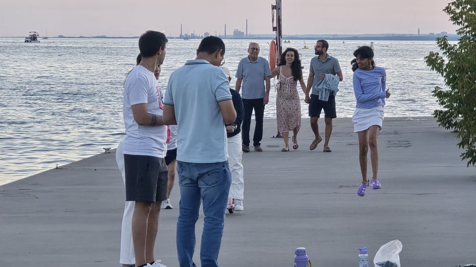 Neighbours walking and talking along the wide concrete deck of the quay