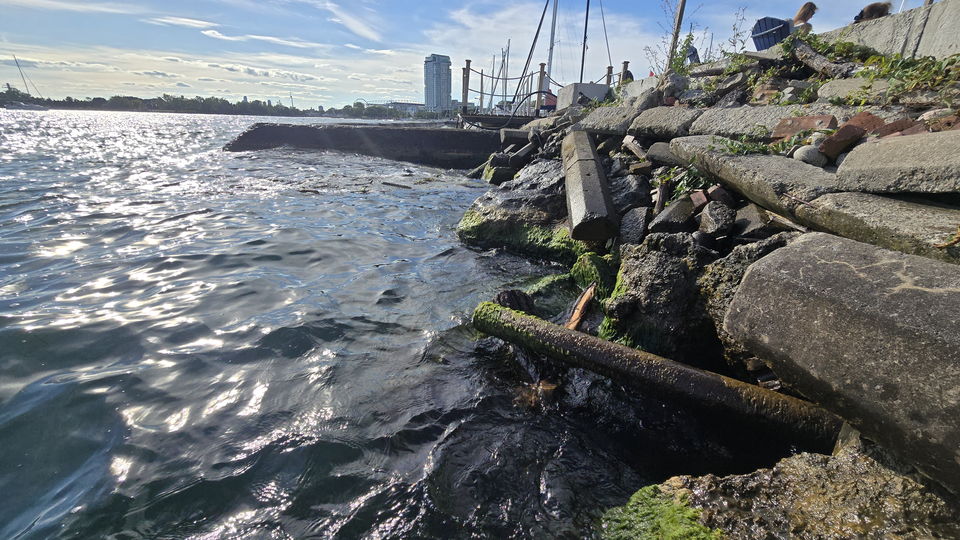 The rubble and armour-stone shoreline running alongside the quay toward the city