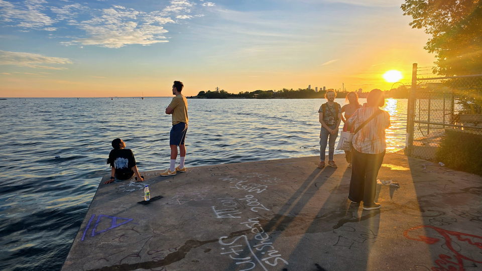 People gathered on the quay deck watching the sun set over the lake